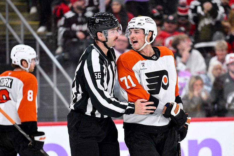 Nov 29, 2025; Newark, New Jersey, USA; Philadelphia Flyers right wing Tyson Foerster (71) is restrained by linesman Julien Fournier (56) during the third period against the New Jersey Devils at Prudential Center. Mandatory Credit: John Jones-Imagn Images