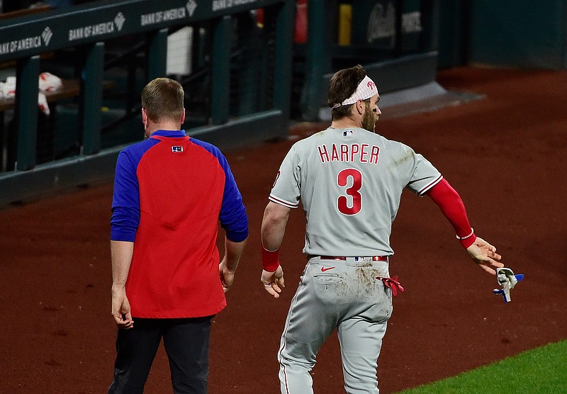Apr 28, 2021; St. Louis, Missouri, USA;  Philadelphia Phillies right fielder Bryce Harper (3) tosses his batting gloves on the field as he walks off with a trainer after he was hit by a pitch from St. Louis Cardinals relief pitcher Genesis Cabrera (not pictured) during the sixth inning at Busch Stadium. Mandatory Credit: Jeff Curry-USA TODAY Sports