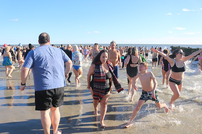 Plungers triumphantly emerge from the frigid surf during the First Dip tradition.