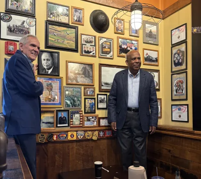 George Whitehair and Dr. Francis Jeyaraj, members of the Boston Legacy Foundation, pose with a portrait of Dr. Frank Erdman Boston that was recently unveiled at Mission BBQ’s King of Prussia location as part of a display honoring veterans and first responders. (Photo courtesy of Boston Legacy Foundation)
