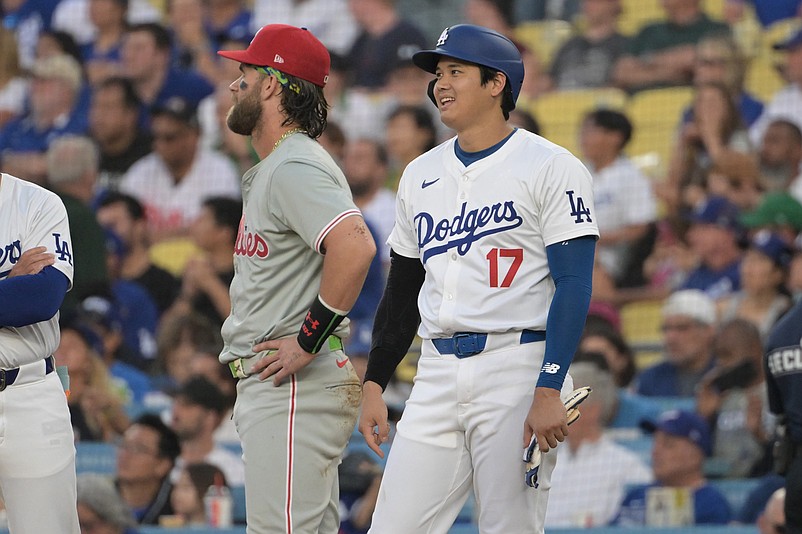 Aug 7, 2024; Los Angeles, California, USA;  Los Angeles Dodgers designated hitter Shohei Ohtani (17) laughs with Philadelphia Phillies first baseman Bryce Harper (3) as they wait for a replay in the first inning at Dodger Stadium. Mandatory Credit: Jayne Kamin-Oncea-USA TODAY Sports