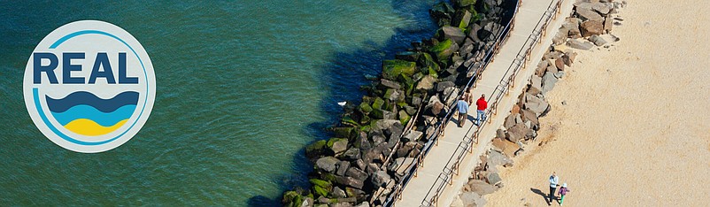 NJDEP/An aerial view of a boardwalk with a jetty on one side and a sandy beach on the other side.