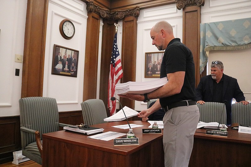 Frank Donato, the city's chief financial officer, places copies of the proposed 2026 municipal budget on the City Council table.