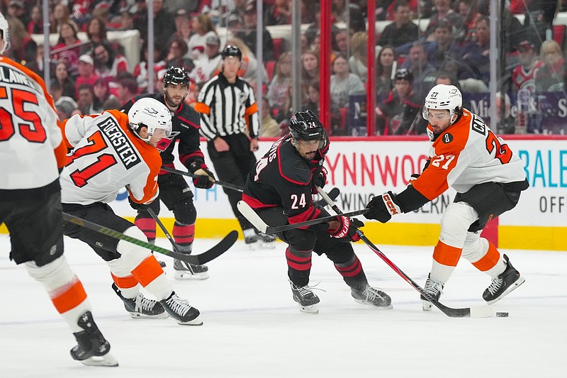 May 2, 2026; Raleigh, North Carolina, USA; Carolina Hurricanes center Seth Jarvis (24) skates with the puck between Philadelphia Flyers left wing Noah Cates (27) and right wing Tyson Foerster (71) during the third period at Lenovo Center. Mandatory Credit: James Guillory-Imagn Images