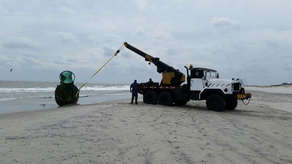 An Ocean City field operations crew devises a way to tow a massive navigational buoy off the beach in advance of last week's coastal storm.