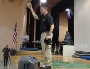 Sgt. Brian Hopely holds up a honeydew melon that survived a fall from overhead with the help of a bicycle helmet.