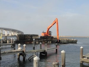 An excavator scoops mud from the mouth of Snug Harbor on Friday, Nov. 6.