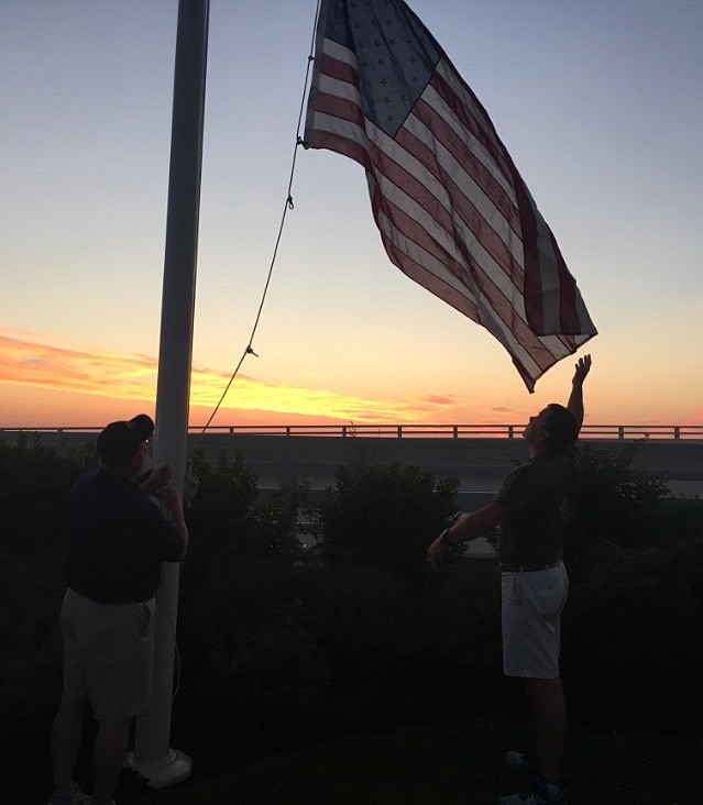 Tom Tumelty. left, and Tom Kennedy as they raise the American Flag at dawn.