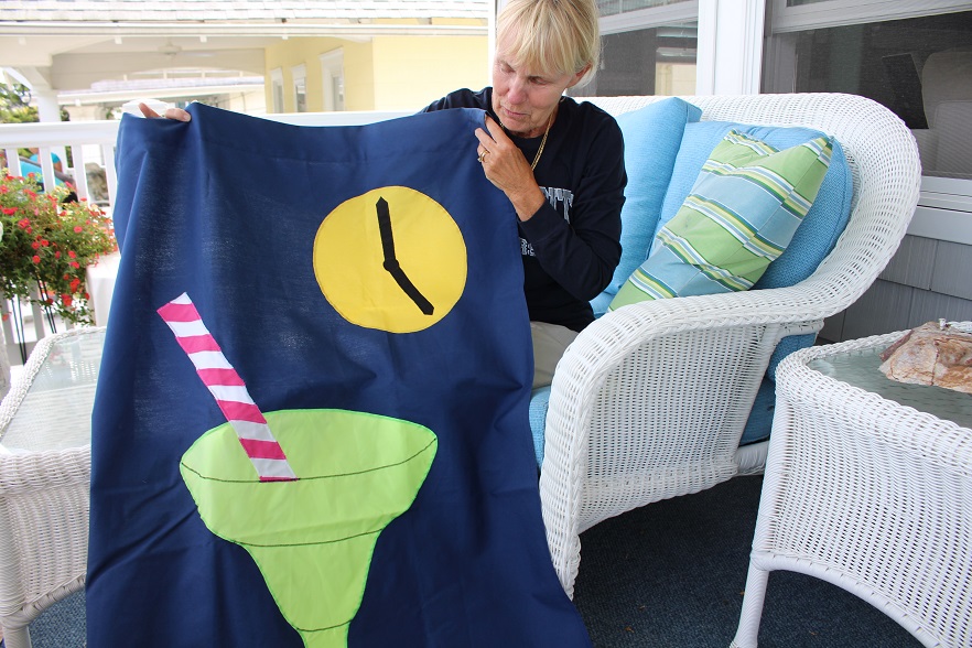 Pam Moran shows of the custom college flag she made to commemorate the schools attended by her children.