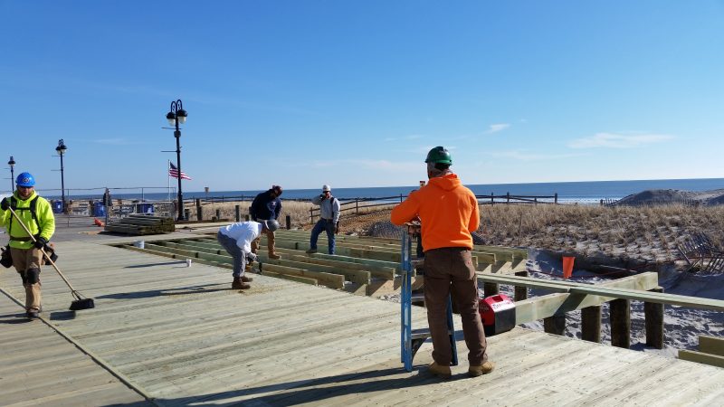 Construction workers are replacing old planks with new timber.