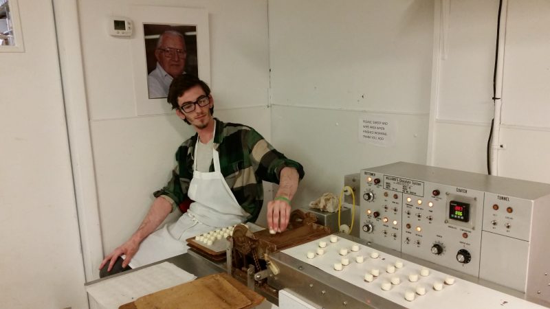 Trevor Blomdahl places candy centers on a conveyor belt before they are dipped in chocolate.