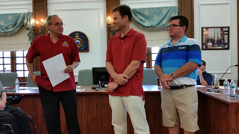 Ocean City High School girls swim coach Steve Warrington, center, accepted honors on behalf of his South Jersey championship team from members of City Council, including Keith Hartzell, left, and Tony Wilson.