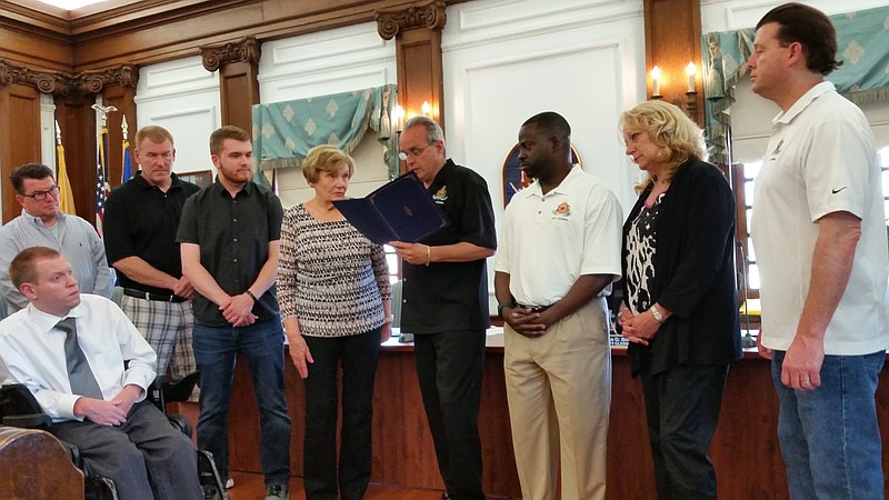 Councilman Keith Hartzell reads a resolution honoring the late Joseph A. Somerville, while members of Somerville's family and City Council listen.