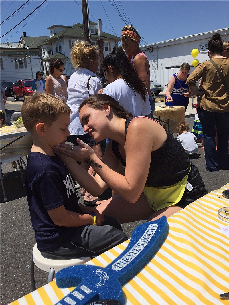 Angelique Matlack paints the face of a happy child in attendance 