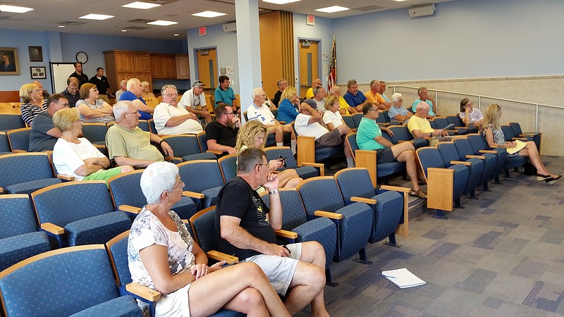 Audience members listen to a presentation on the city's $20 million dredging program during the town meeting at the public library.