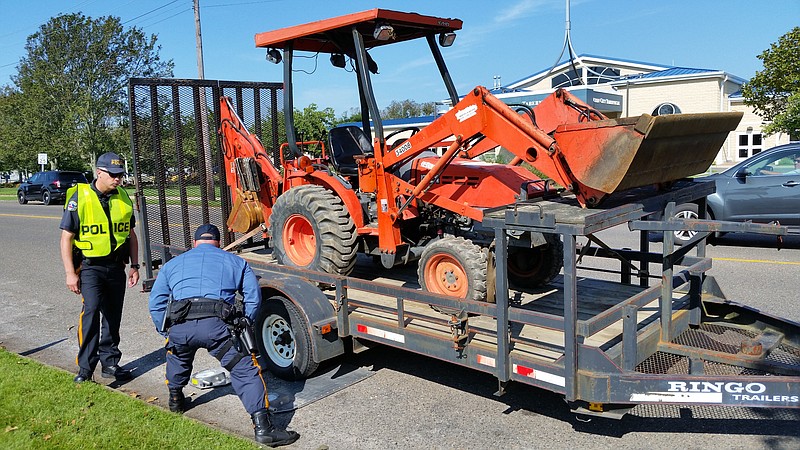 Officers check the weight of a backhoe being towed by a pickup truck to see if it exceeded the 8,000-pound limit.