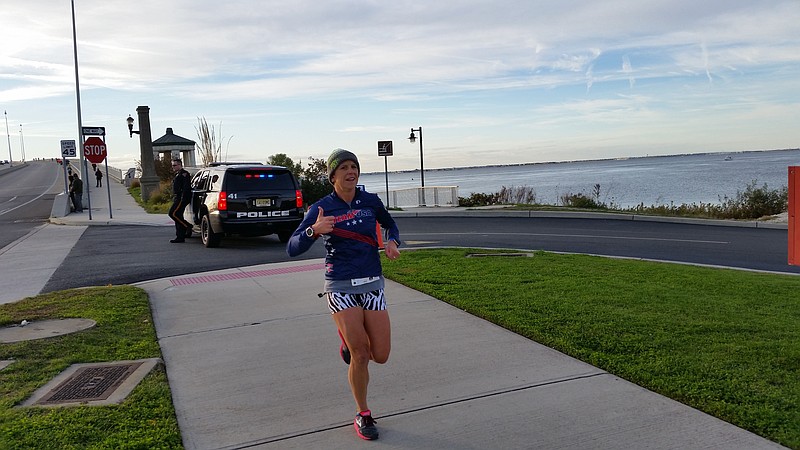 Carrie Merritt, of Marmora, gives a thumbs-up sign while  breezing toward the finish line as the top female runner.