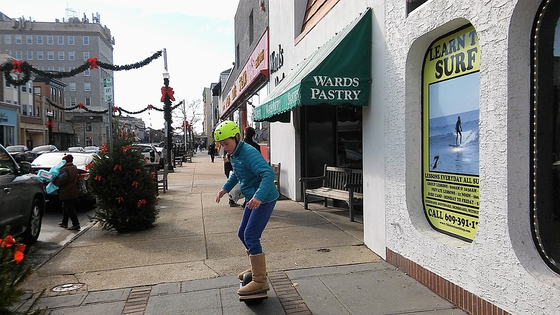 Mia Gallagher tries out a Onewheel, like a motorized skateboard, outside of the surf shop.