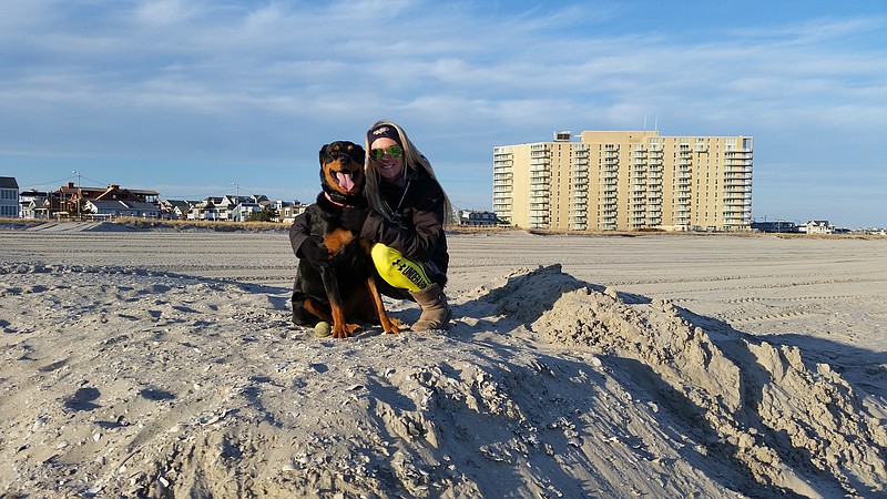 Ocean City resident Erica Reis gives her dog, Rayna, a hug while sitting on a pile of new sand.