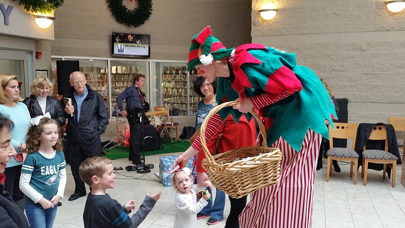 Katrina Steinbacher, a 9-foot-tall stiltwalker, hands out gifts to children while entertaining the crowd.