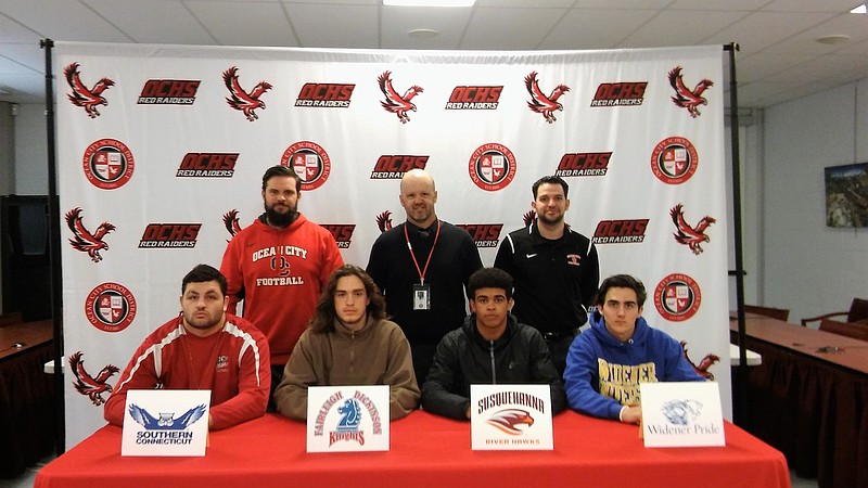 Ocean City High School seniors Jim Rice, Harry Pfeifle, Issac Robertson and Bobby Shallcross commit to colleges to play football during a ceremony Tuesday morning at the high school. In back from left Sean Matthews - coach, Kevin Smith-head coach and coach Frank Lasasso.