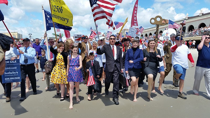 Attired in business wear, the plunge participants march into the waves to officially "open" the ocean for the summer tourism season.