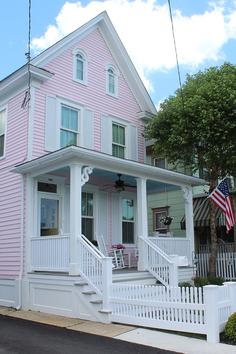 The historic pink house features a stately front porch.