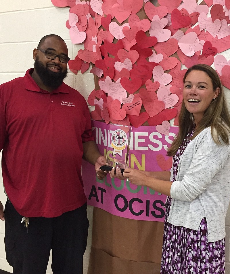 OCIS Guidance Counselor and one of the Kindness Captains, Shannon Pruitt (right) and OCIS Support Staff Member of the Year and Kindness Ambassador Nick McClellan hold the trophy by the Kindness Tree.   