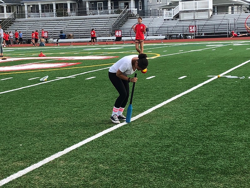 Freshman Ciera James spins five times on the “dizzy bat” during the relay obstacle course before she moves to the ball toss.