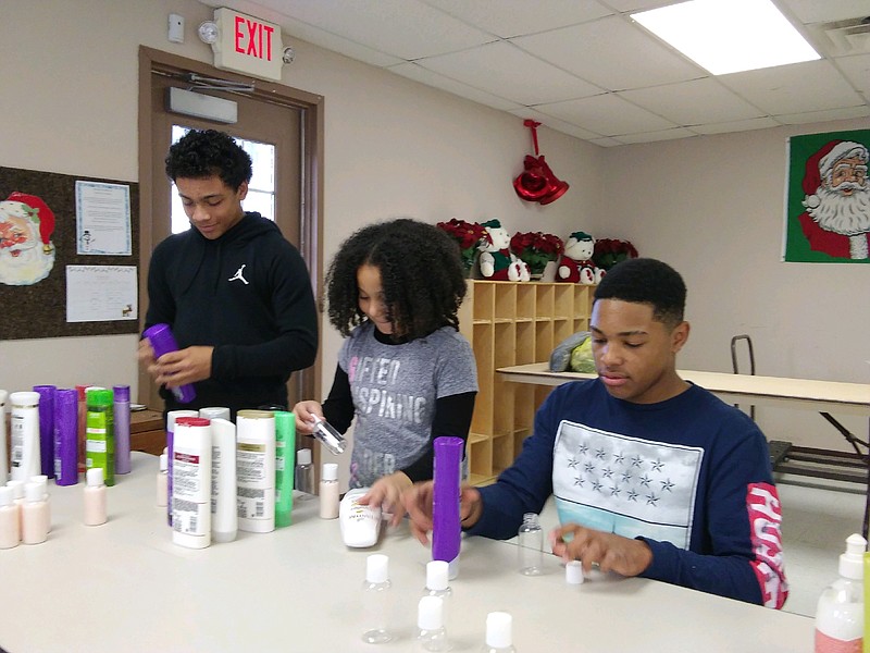 Jeramiah Sinclair, 13, his friend, Jaevien Swain, 12, and his sister, Jayda Graves, 9, all of Somers Point squeeze shampoos into trial size containers.