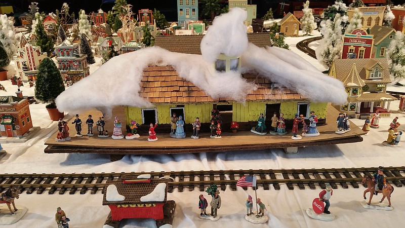 Tiny people wait to board a train at a snow-covered station in this winter wonderland.