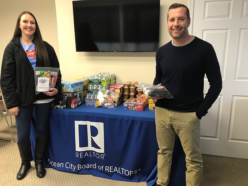 Kerry Sullivan, of Angels in Motion, and Damon Bready, president of the Ocean City Board of Realtors, stand alongside some of the donations for the “Blessing Bags.” (Courtesy Ocean City Board of Realtors)   
