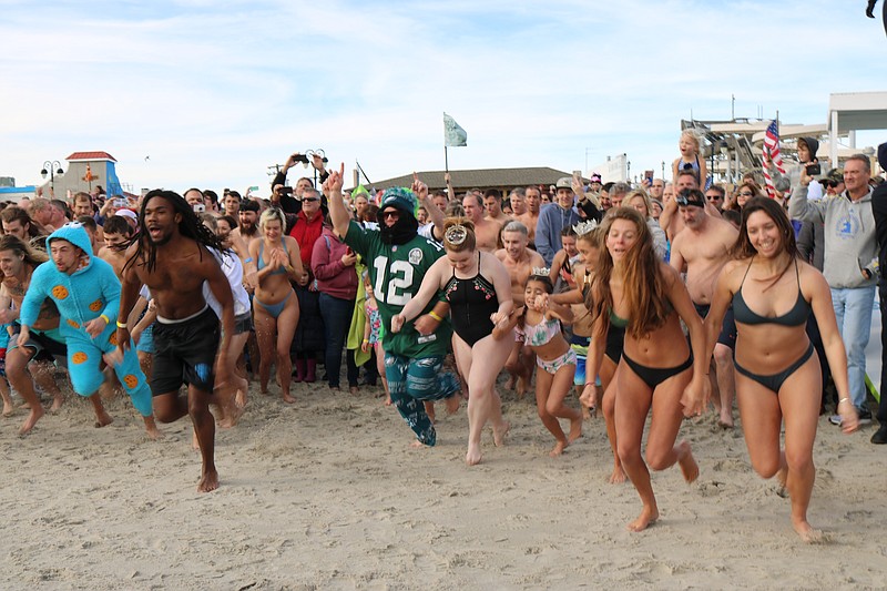 Revelers take off to the ocean for an icy dip.