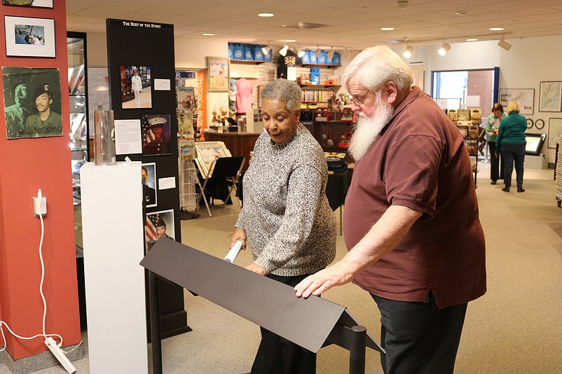 Harris and Loeper look at a display board that explains some of the history of the Ford family.