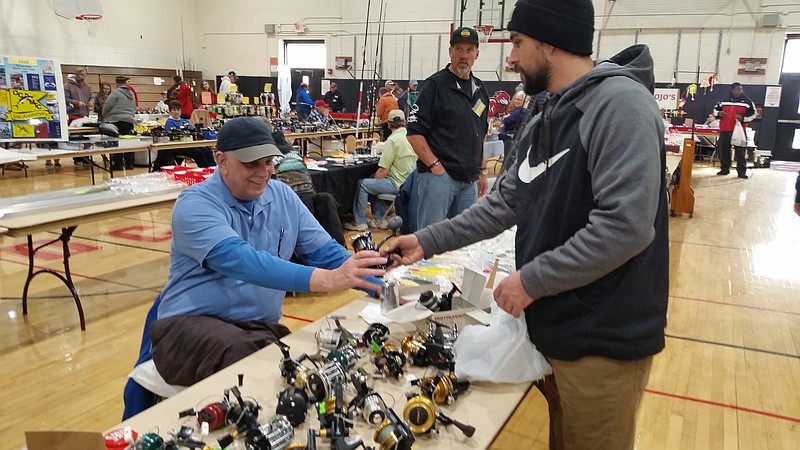 Vendor Mike Carman, left, and customer Tyler Quinn, of Lumberton, N.J., look over a fishing reel.