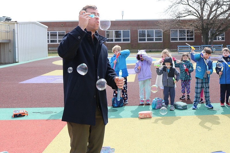 Teacher Randy Kohr blows bubbles with the students for autism awareness.