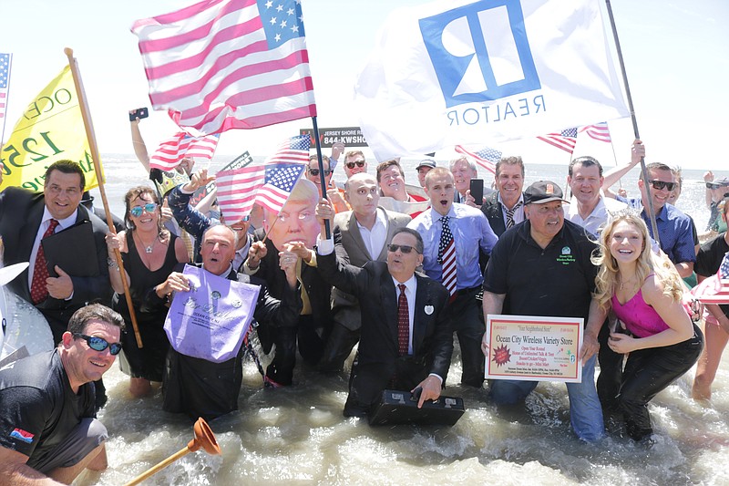 In a scene from 2019, John Walton, holding the American flag, leads the celebrants in the zany event that traditionally opens Ocean City's summer tourism season.