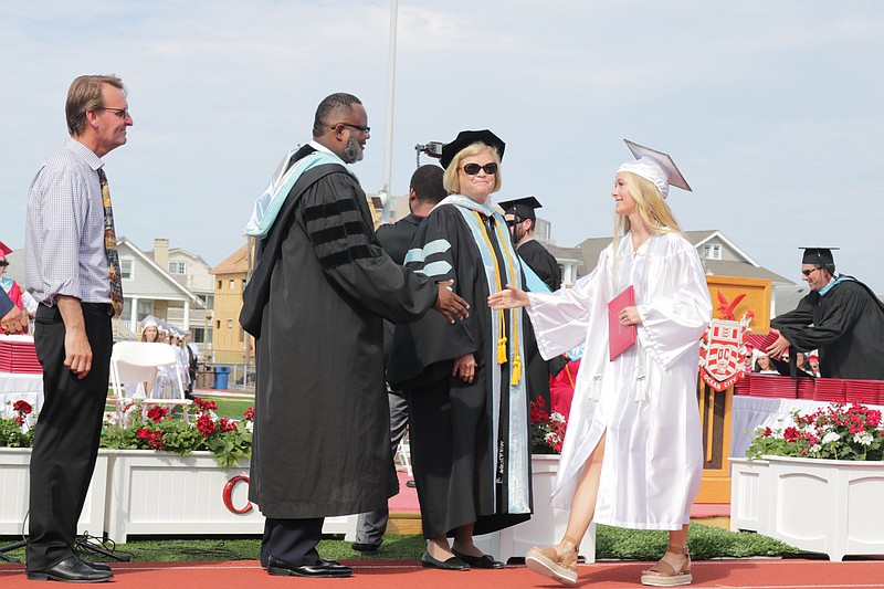 Then Education Commissioner Dr. Lamont Repollet and Schools Superintendent Kathleen Taylor shake a graduate's hand in 2019.