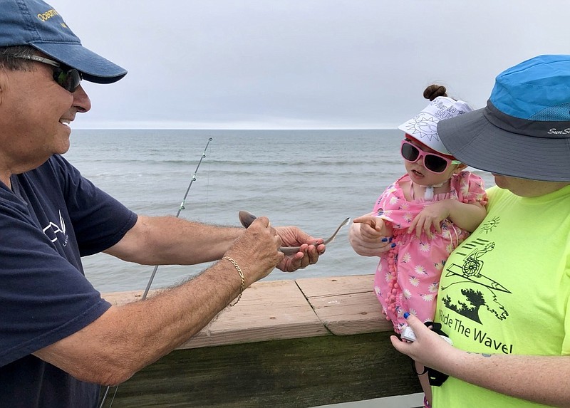 Shannon Sokolski, a therapeutic recreational therapist with NJ WAVE, holds Makenzi, 4, who touches a sand shark caught by Frank Pizzutilla, Ocean City Fishing Club president.
