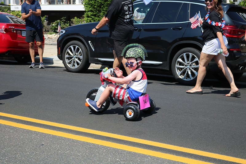 A youngster decked out in red, white and blue cruises down the street on his tricycle in the 2019 bike parade.