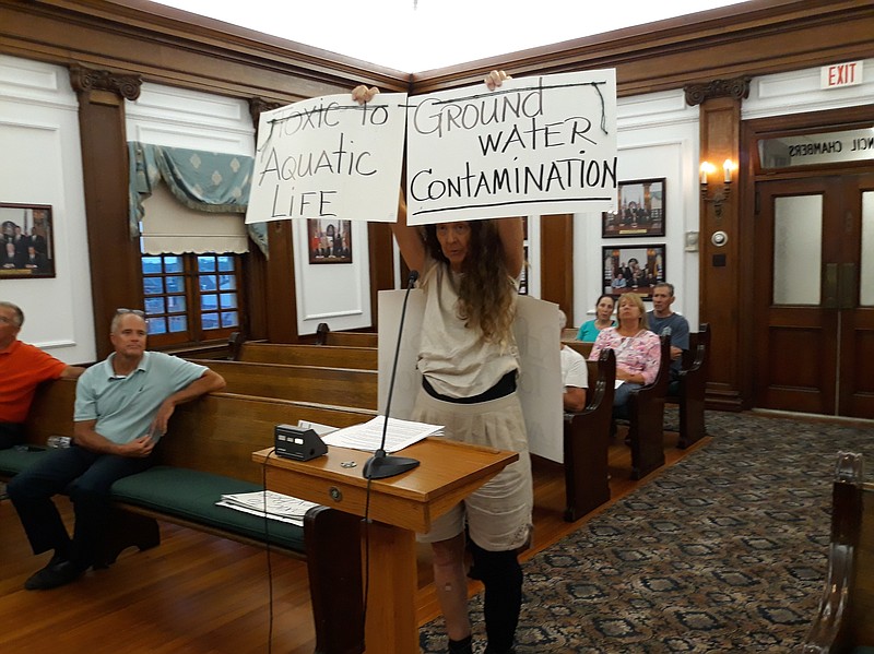 Donna Moore holds some of her signs warning of the dangers of pesticides containing toxic chemicals.