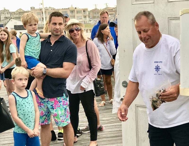 Ocean City Fishing Club member Dan Moore shows a wary youngster some of the bait that pier anglers use.