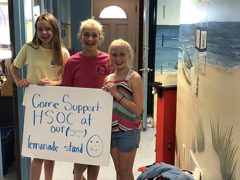 During a recent visit to the Humane Society, the girls display a sign urging people to support their lemonade stand.