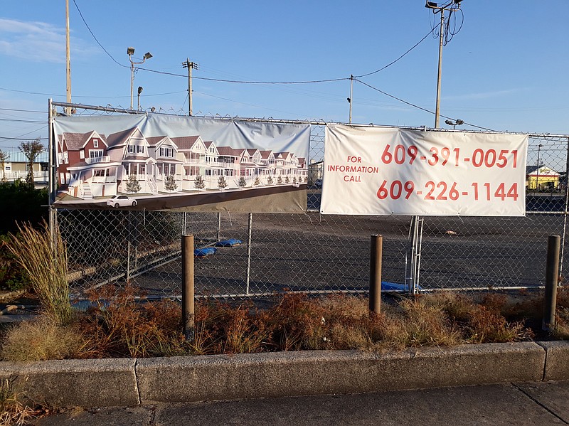 A banner showing what the new houses will look like is attached to a chain-link fence surrounding the property.