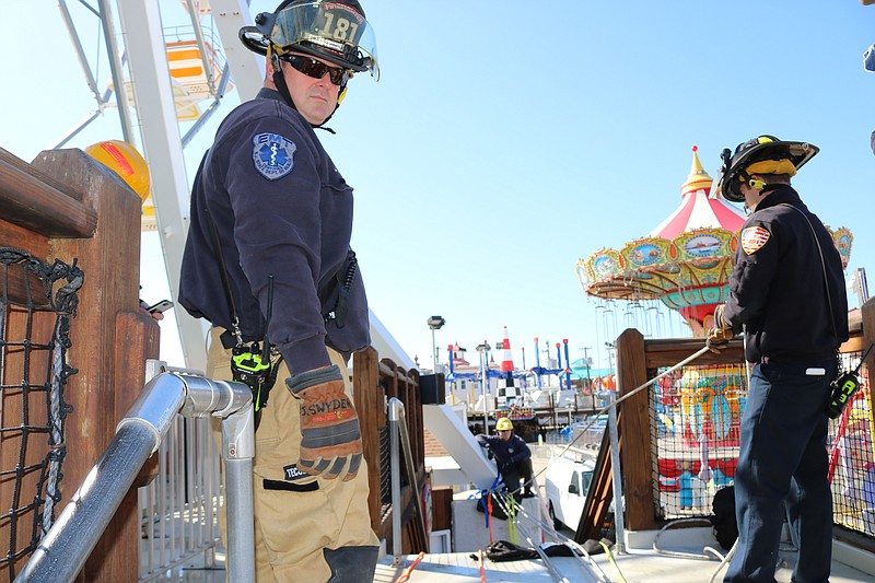 Firefighters work on securing ropes to create a pulley system from the ride to the High Seas amusement.