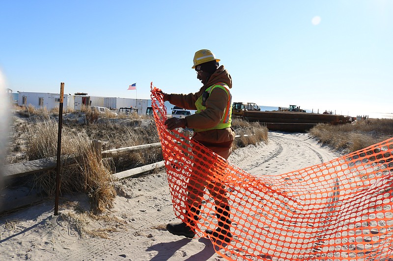 Milton Johnson, a shoreman for Great Lakes Dredge &amp; Dock Co., the project's contractor, puts up a barrier at the entryway to the 59th Street beach.