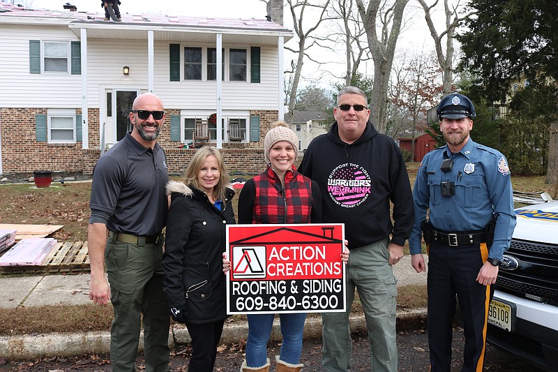 From left, Ocean City Police Lt. Pat Randles, Edie, dispatcher Amber Adoranto's mother, Amber, Capt. Charlie Simonson and Officer Randy Clark stand in front of the Ocean View home as workers install a new roof. 