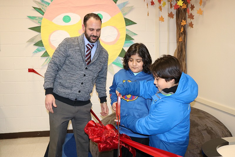 Principal Michael Mattina helps Edison Castillo, of Ocean City, and his brother, Hector, cut the ribbon.