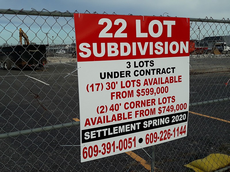 A sign attached to a chain-link fence surrounding the property gives a sneak preview of the housing project.