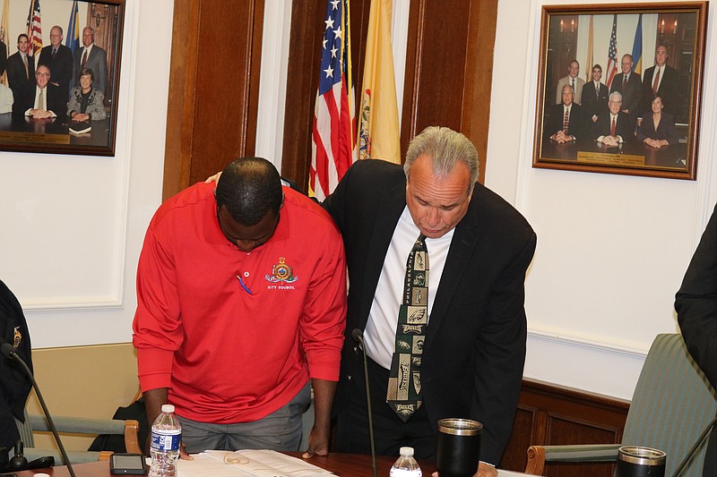 Antwan McClellan joins fellow Council member Keith Hartzell in pray at the start of the meeting.